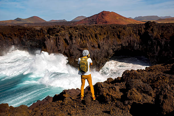 masculino turista fotografando rochoso costa na ilha de lanzarote - cargo canarias imagens e fotografias de stock