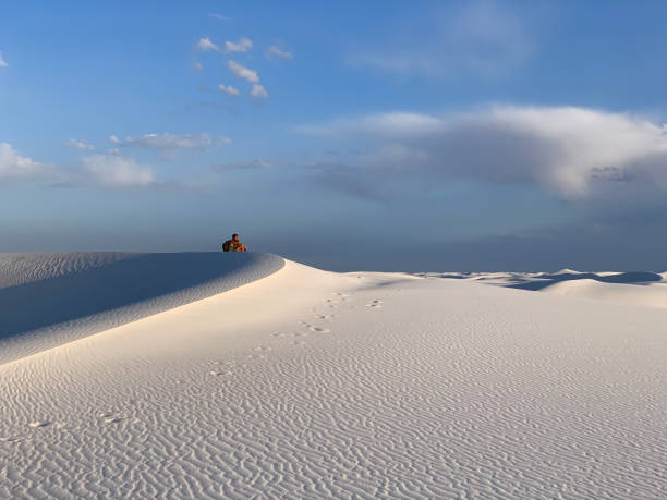 Male Tourist Sitting on Sand Dune in White Sands National Park in New Mexico, USA stock photo