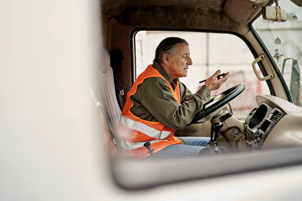 Male Trucker in Early 60s Using Phone in Cab stock photo