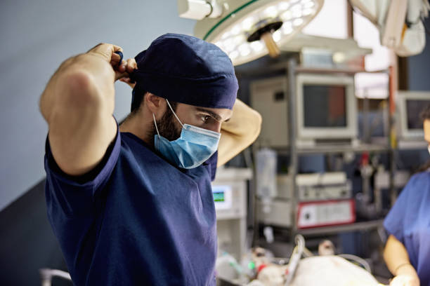 Male Veterinarian Putting on Surgical Cap Before Procedure stock photo