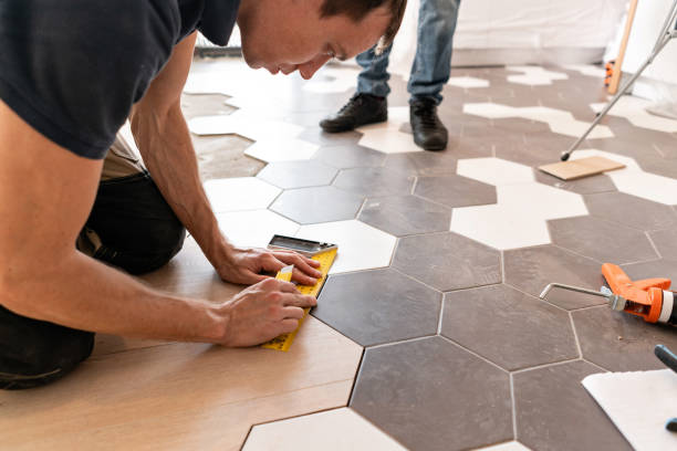 Male worker installing new wooden laminate flooring. The combination of wood panels of laminate and ceramic tiles in the form of honeycomb. Kitchen renovation stock photo