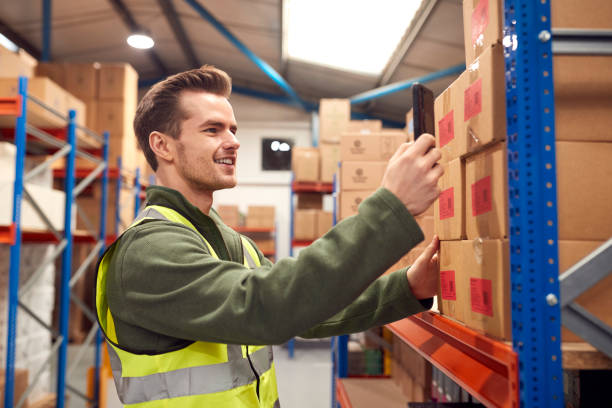 Male Worker Wearing Inside Warehouse Scanning Stock Barcode On Shelves Using Digital Device Or Phone stock photo