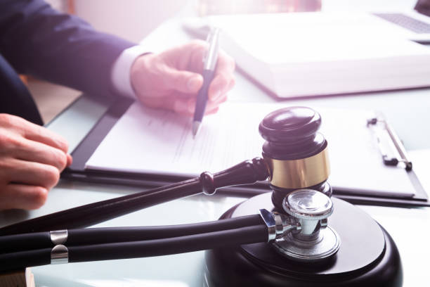 Mallet And Stethoscope Over Sound Block In Court Judge Writing On Legal Documents With Mallet And Stethoscope Over Sound Block In Court legislation stock pictures, royalty-free photos & images