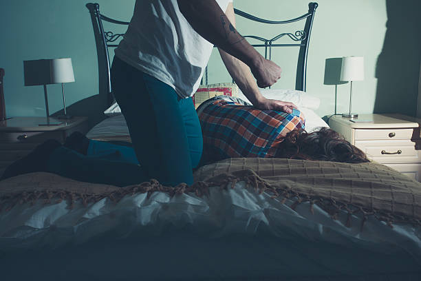 Man abusing his wife on a bed stock photo
