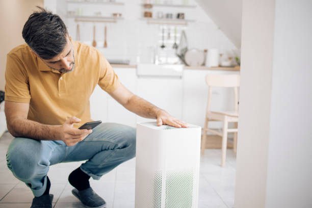 Man adjusting his new air humidifier, using a smart system stock photo