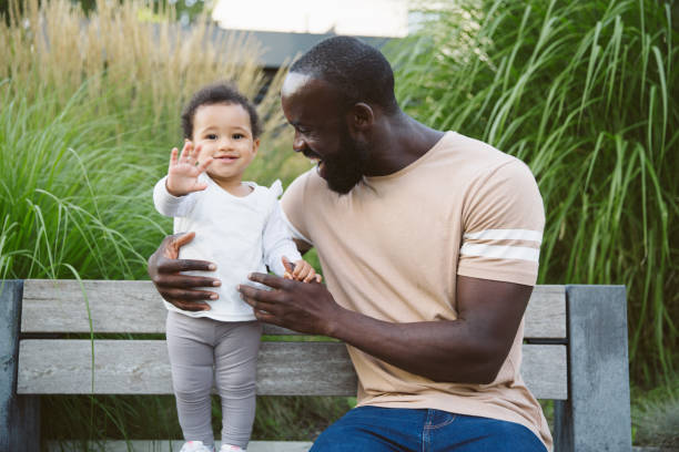 Man and baby girl sitting on a bench having fun stock photo