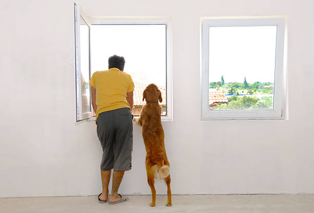 Man and dog looking through window stock photo