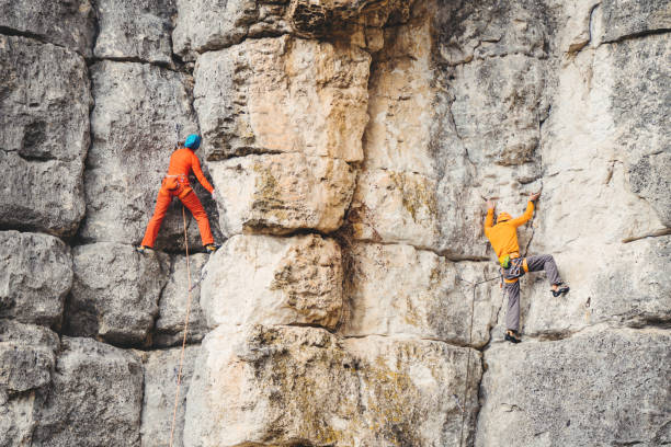 Man and woman climb a rock. Athletic woman and man in colorful sportswear climbs a rock with rope. Sport climbing, lead. Side view. Crimea. rock face stock pictures, royalty-free photos & images