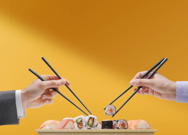 Man and woman eating sushi together stock photo