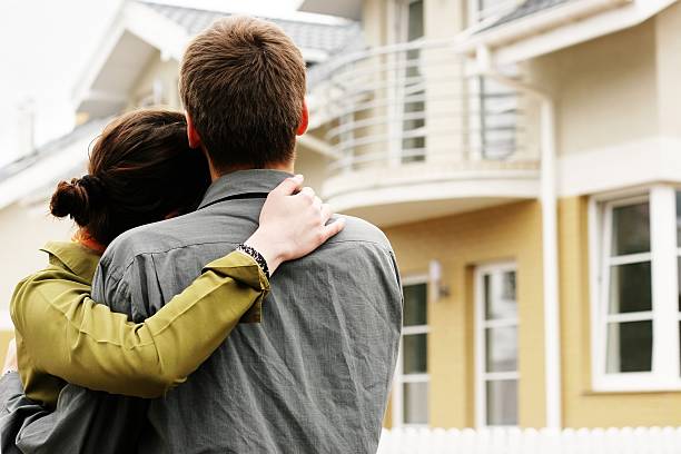 Man and woman hugging in front of a house couple in front of one-family house in modern residential area in front of stock pictures, royalty-free photos & images