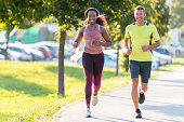 istock Man and woman running in public park. 1363750475