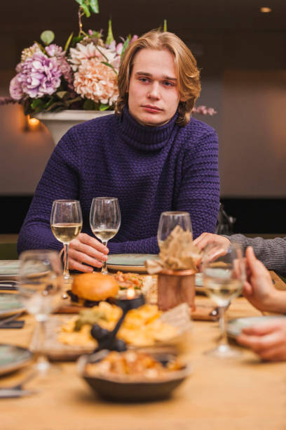 Man at a friends dinner with a glass of white wine stock photo