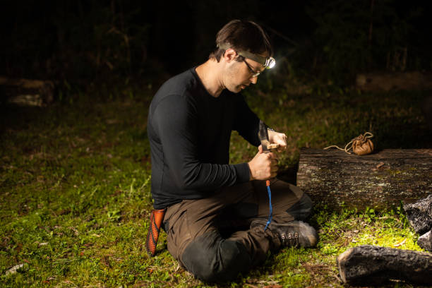 Man at night prepares wood for a camp fire stock photo