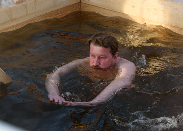 man bathes into cold water of ice-hole on epiphany day. - ice bath in natural frozen lake bildbanksfoton och bilder