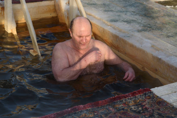 man bathes into cold water of ice-hole on epiphany day. - ice bath in natural frozen lake bildbanksfoton och bilder