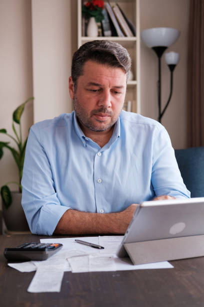 Man calculating personal expenses at home stock photo