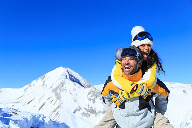 Man carrying on shoulders his girlfriend on top snow mountain stock photo