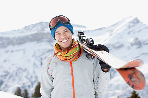 man carrying skis - posing with ski stockfoto's en -beelden