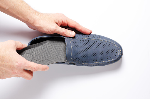 A man changes the insole in his shoes. White background, closeup