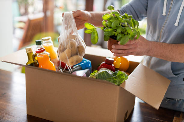 Man checking his fresh food delivery Young man unpacking boxes of food at home grocery store stock pictures, royalty-free photos & images