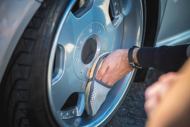 A man cleans the wheels of his car. Dropped silver car on air suspension. stock photo