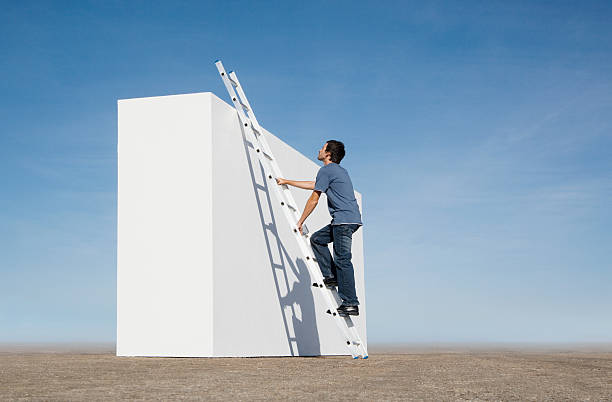 Man climbing ladder against wall outdoors  ladder stock pictures, royalty-free photos & images