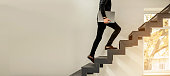 istock man climbing on a stairs and holding a laptop. 1362372148