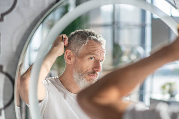 hombre peinando su cabello por la mañana - cabello gris fotografías e imágenes de stock