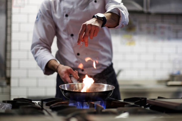 un hombre cocina freidoras cocina en un fuego de cocina. - chef fotografías e imágenes de stock
