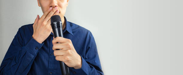 Man covering mouth, holding microphone Man covering mouth, holding microphone how do you say shut up in japanese stock pictures, royalty-free photos & images