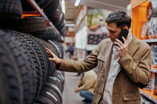 man customer choosing new tires in the auto shop - köpa däck bildbanksfoton och bilder