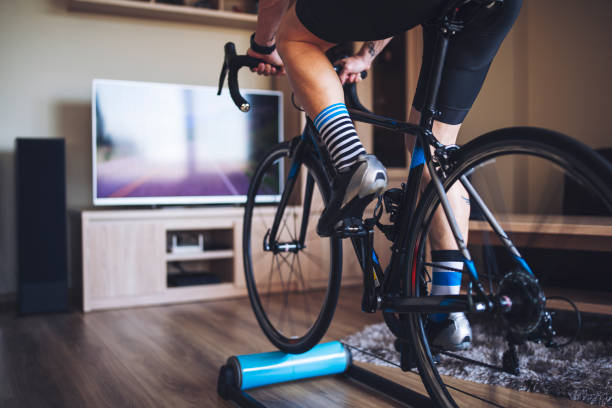 Man Cycling Indoor With Exercise Bike Trainer. Unrecognizable man cycling indoor with exercise bike trainer. peloton stock pictures, royalty-free photos & images