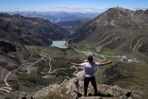 man defeated Neunerkogel (2604m) and rejoices in his victory. The climber enjoys views of the village of Kuhtai and the Langental Reservoir in western Austria. Feeling satisfied with hard work. stock photo