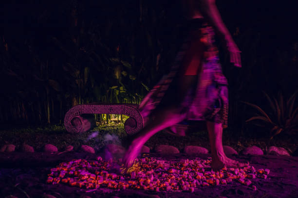 Man doing firewalking ritual- a ceremony of walking barefoot over a bed of hot coals or stones Man doing firewalking ritual- a ceremony of walking barefoot over a bed of hot coals or stones during night firewalking stock pictures, royalty-free photos & images