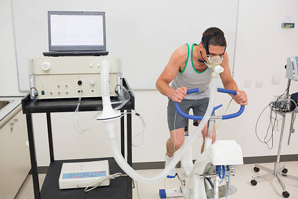 Man doing fitness test on exercise bike Man doing fitness test on exercise bike at the medical centre sport scientist stock pictures, royalty-free photos & images