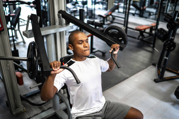 Man doing strength workout exercise in gym Man doing strength workout exercise in gym exercise machine stock pictures, royalty-free photos & images