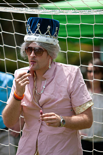 uomo vestito come queen elizabeth applica il lucidalabbra - queen elizabeth foto e immagini stock