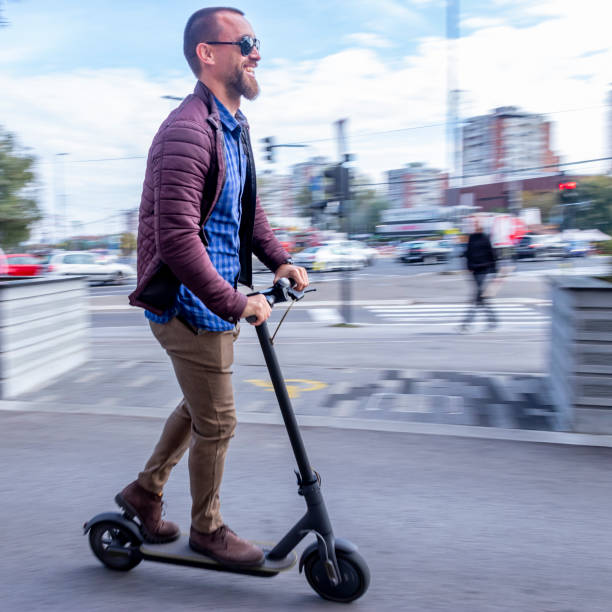 Man dressed casually smiling while riding electric scooter stock photo