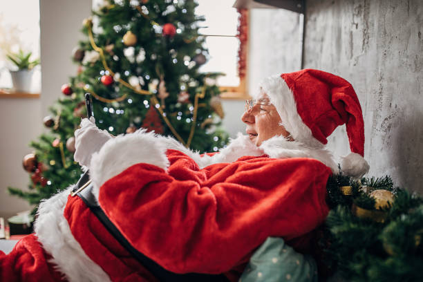 man klädd som jultomten med mobiltelefon hemma - sms imposter elderly bildbanksfoton och bilder
