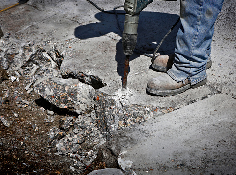 Road construction: Street worker is drilling concrete