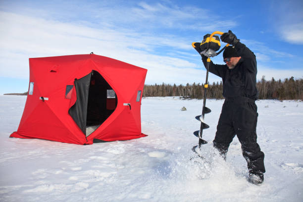 Man Drilling Hole In Ice With Auger For Ice Fishing In Manitoba Canada stock photo