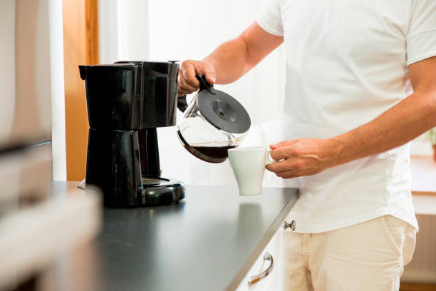 Man drinking coffee in the morning Man in the kitchen pouring a mug of hot filtered coffee from a glass pot. Having breakfast in the morning coffee maker stock pictures, royalty-free photos & images