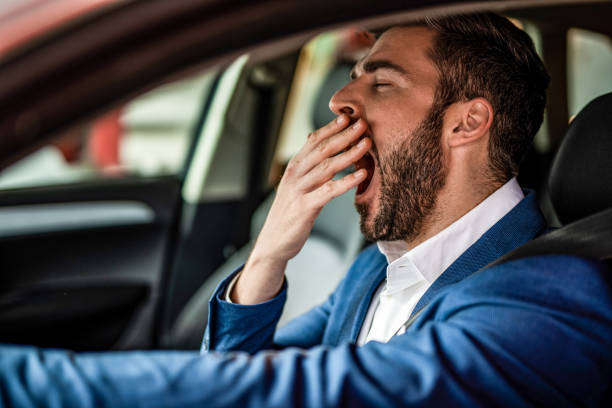 Man driving a car and yawning. stock photo