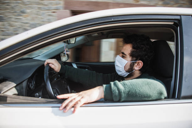Man driving a car with face mask stock photo