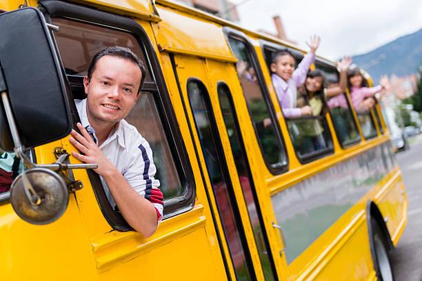 Man driving a school bus Happy man driving a school bus with a group of students school bus driver stock pictures, royalty-free photos & images