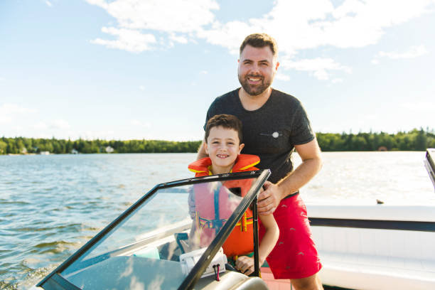 man driving boat on holiday with his son kid - chalana imagens e fotografias de stock