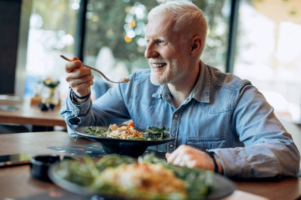 Man eating healthy  meal in the restaurant. Mid age man eating healthy meal. stock photo