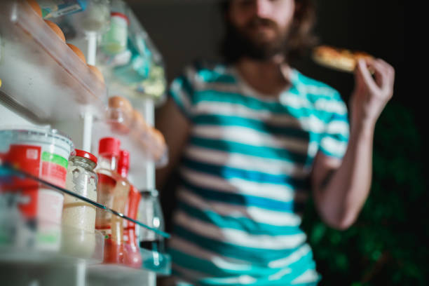 Man eating in front of the refrigerator late night stock photo