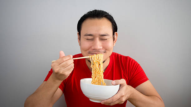 Man eating instant noodles. stock photo