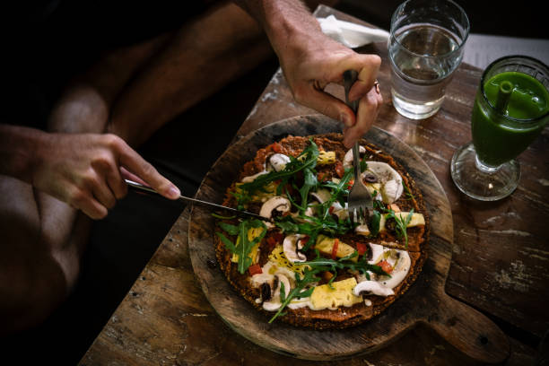 Man eating raw vegan pizza on wooden table 